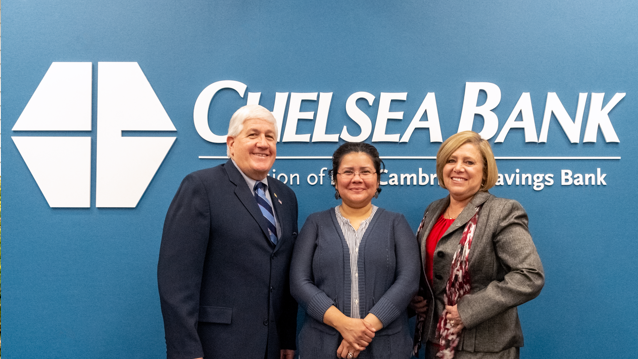 male banking professional with two women posing in front of Chelsea Bank logo