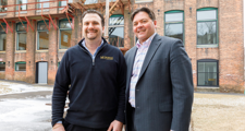 two men standing in front of an old mill building that was redeveloped