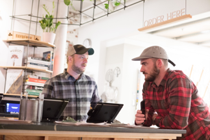 man talking to another man who is leaning on a counter