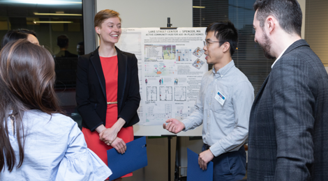 female graduate student with two male graduate students standing in front of an easel as they chat