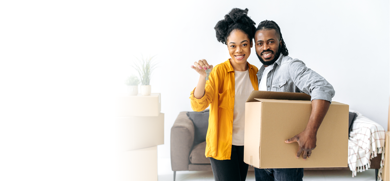 Woman holding a house key standing next to a man holding a moving box