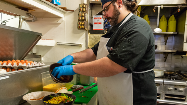 male chef in restaurant kitchen preparing a meal for a patron