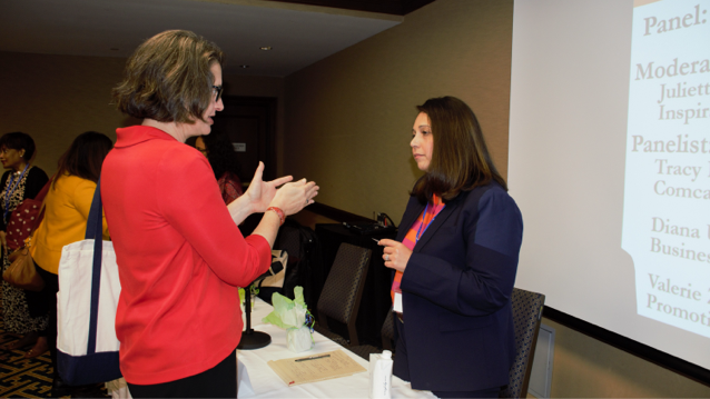 two female attendees at women's conference standing facing each other as they chat