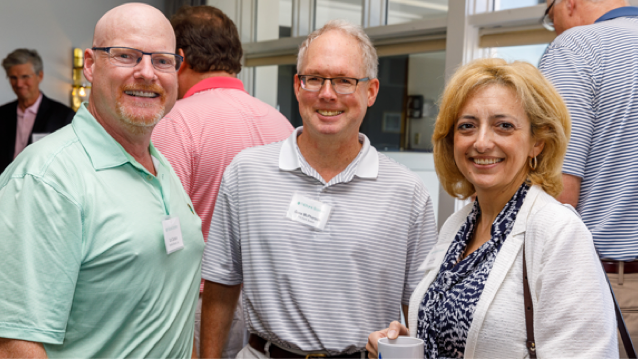 two smiling men standing next to a smiling woman