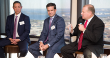 three male members seated as part of a panel speaking at an insurance company meeting