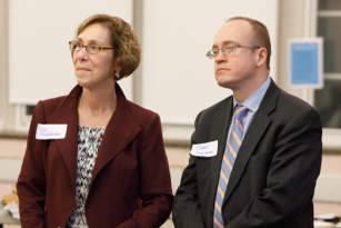 woman and man who are part of housing and community investment team standing and listening to a speaker