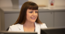 Female FHLBank Boston employee seated and facing computer screens.