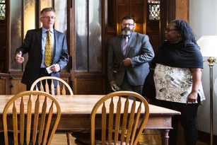 female advisory council member speaking to two men as they are standing near a table