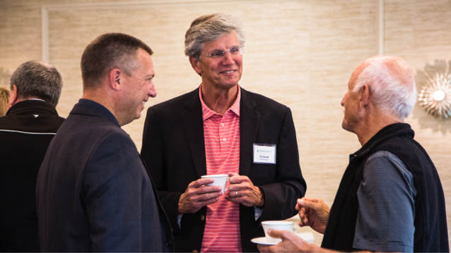 FHLBank Boston president holding a cup while standing between two representatives from member financial institutions.