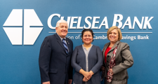 male bank leader with two women posing  in front of Chelsea Bank logo