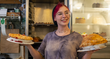 woman smiling as she holds two pies