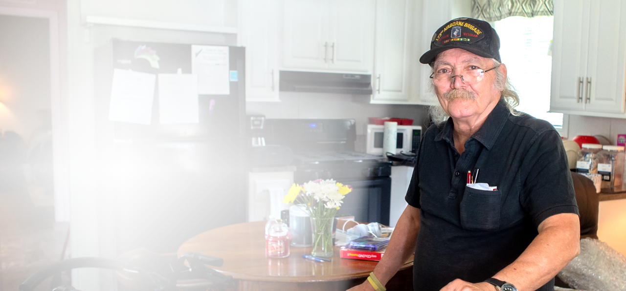 male veteran sitting at a kitchen table in his home