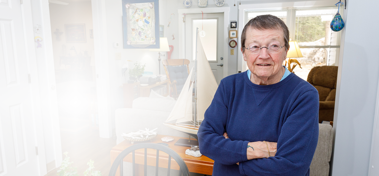 senior female wearing blue sweater standing with her arms folded